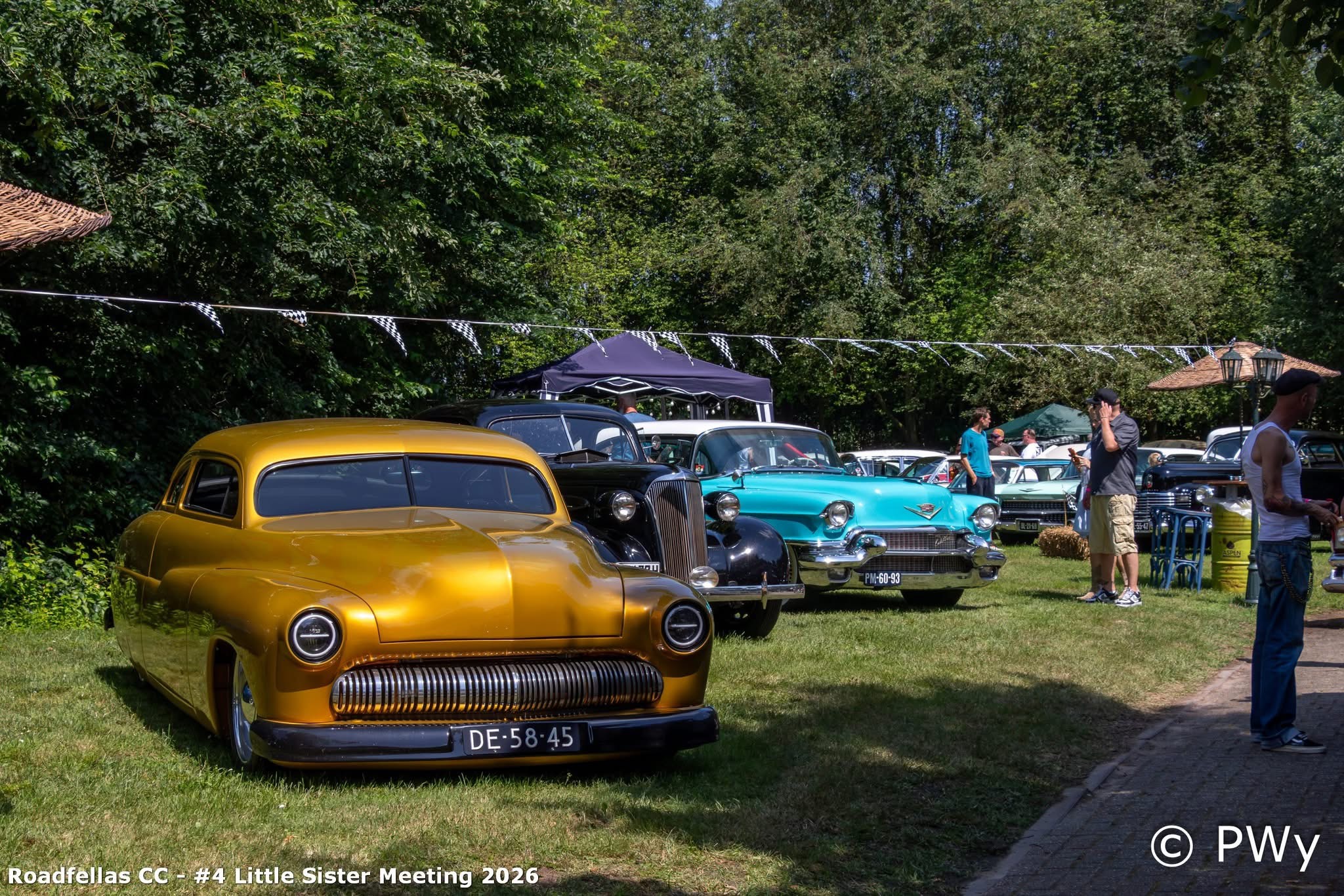 Gouden Mercury lead sled naast zwarte Packard en turquoise Cadillac op het gras