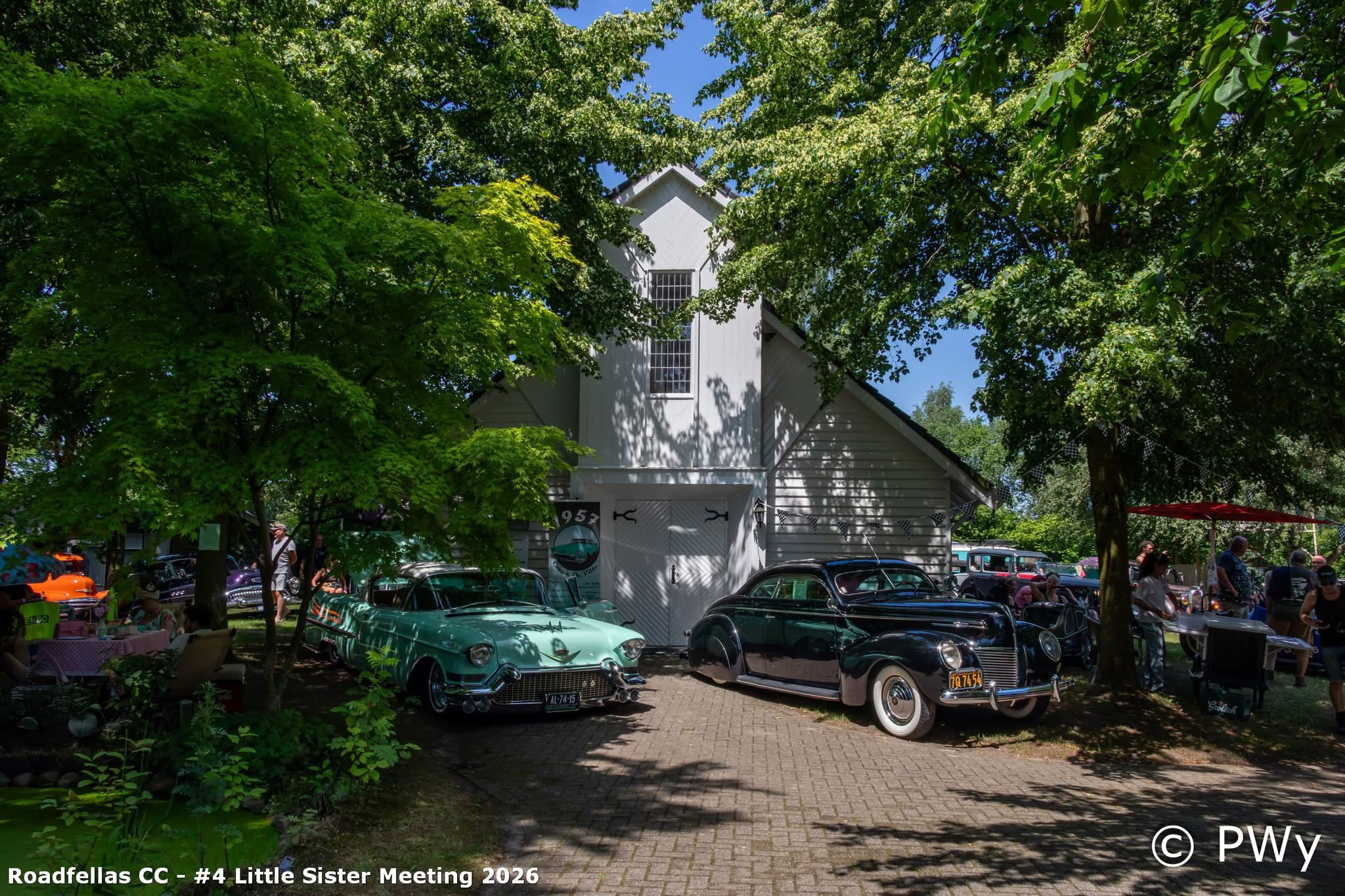 Het witte kerkje met mint-groene Cadillac en zwarte classic ervoor onder de bomen