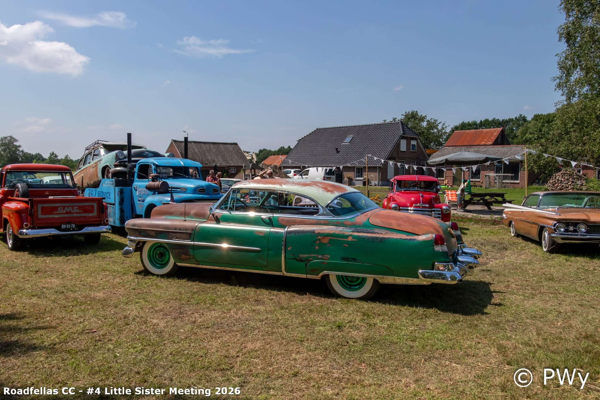 Groene patina Cadillac op het grasveld naast een rode en blauwe truck tijdens een privé event